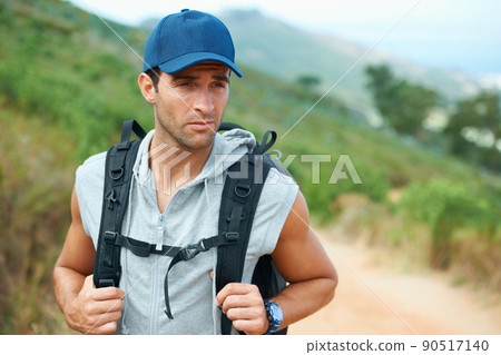 Carrying on down the road.... Young hiker wearing a backpack looking sideways. 90517140