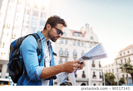 Where am I. Cropped shot of a handsome young man looking at a map while touring a foreign city. 90517143