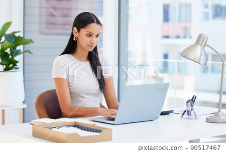 Focused and ready to tackle this day. Shot of a young businesswoman using her laptop at work. 90517467