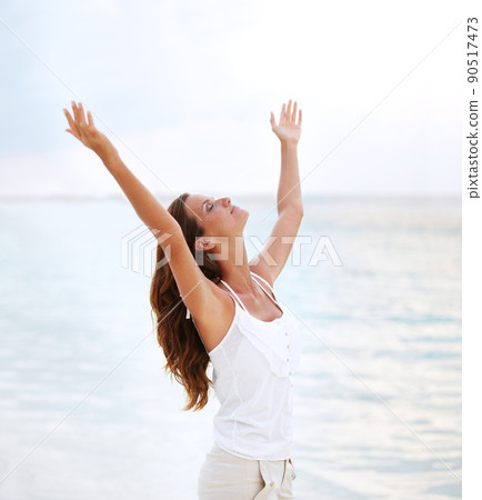 Finding release. Shot of a beautiful young woman with her arms raised to the sky. Finding release. Shot of a beautiful young woman with her arms raised to the sky. 90517473