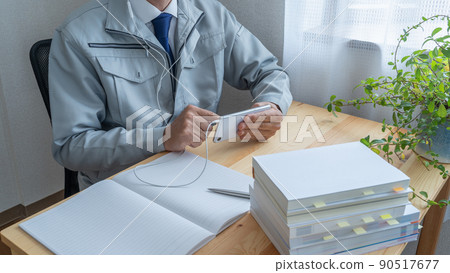 Watching smartphones | Image of a construction businessman aiming to acquire qualifications while working Watching smartphones | Image of a construction businessman aiming to acquire qualifications while working 90517677