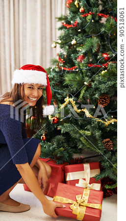 I know hell love his gift. Shot of a beautiful young woman placing a gift under a christmas tree. I know hell love his gift. Shot of a beautiful young woman placing a gift under a christmas tree. 90518061