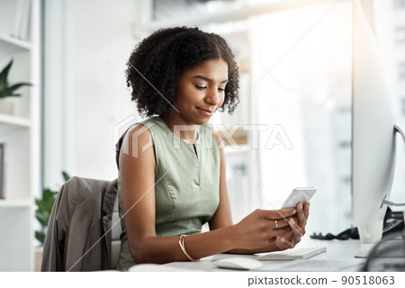The smart way to navigate her work day. Shot of a young businesswoman using a mobile phone at her desk in a modern office. The smart way to navigate her work day. Shot of a young businesswoman using a mobile phone at her desk in a modern office. 90518063