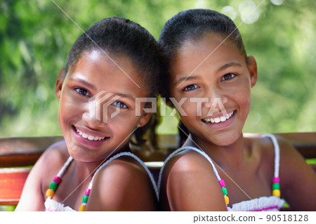 Two of a kind. Cropped portrait of two twin sisters sitting on a park bench. Two of a kind. Cropped portrait of two twin sisters sitting on a park bench. 90518128