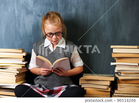 She reads whenever the chance arises. A cute blonde girl reading in class during break surrounded by books. She reads whenever the chance arises. A cute blonde girl reading in class during break surrounded by books. 90518208