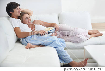 They love chilling at home together. A young couple watching a movie at home. 90518298