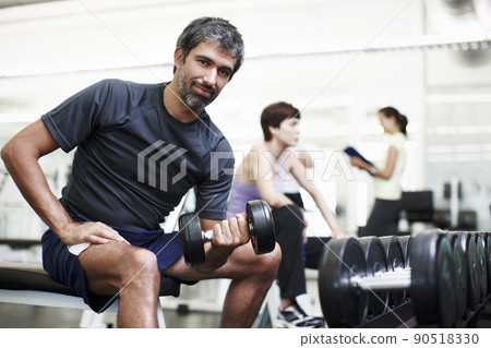 Everyone should hit the gym now and then. Cropped portrait of a handsome young man working out with weights in the gym. 90518330