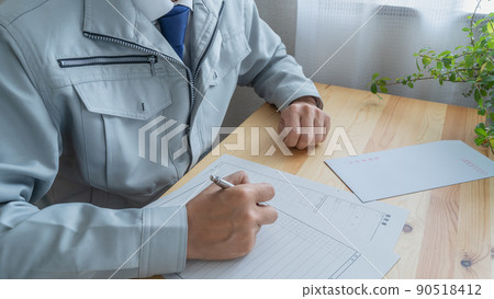 A man in work clothes writing a resume │ Image of construction-related job hunting and job hunting activities 90518412