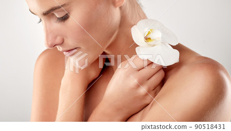 Perfection in the flesh. Closeup studio shot of a beautiful young woman holding an orchid. 90518431