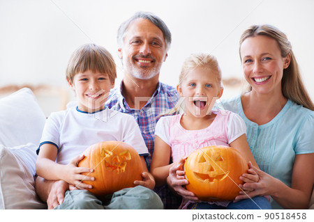 Proud of their pumpin carvings. Portrait of a family of four showing you their carved pumpkins. 90518458