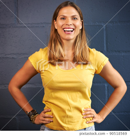 Yellow...the color of happiness. Cropped portrait of a young woman posing against a brick wall background. Yellow...the color of happiness. Cropped portrait of a young woman posing against a brick wall background. 90518569