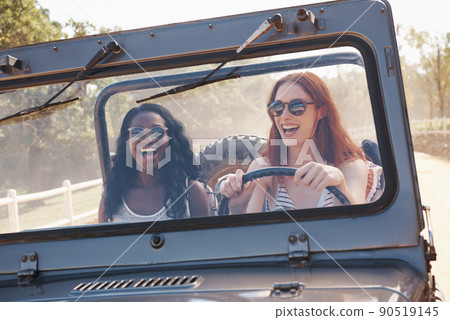 Fun is our fuel. Cropped shot of two laughing woman driving down a dirt road. 90519145