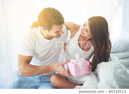 Ive got a little surprise for you. Shot of a loving husband giving his wife a gift. 90519515