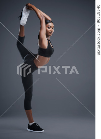 As fierce as she is flexible. Studio portrait of a sporty young woman stretching her body against a grey background. As fierce as she is flexible. Studio portrait of a sporty young woman stretching her body against a grey background. 90519540
