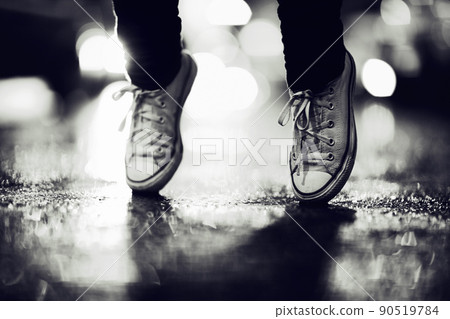 Falling over in the dark. Cropped image of a person wearing sneakers standing on their toes in the street. 90519784