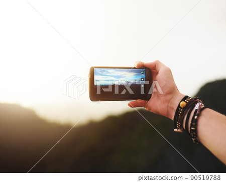 Theres so much beauty to behold in nature. Closeup shot of an unidentifiable man taking a photo on his cellphone outside. 90519788