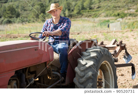 Positive man working on farm tractor 90520731