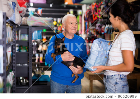 Pet store employee helps an elderly man choose dog food Pet store employee helps an elderly man choose dog food 90520999