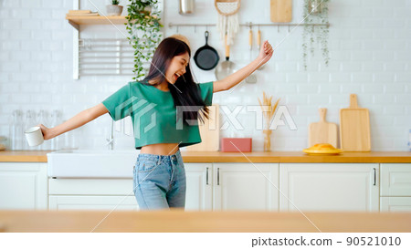 Asian young woman dancing in kitchen room. Female happy and relaxing at free time on weekend Asian young woman dancing in kitchen room. Female happy and relaxing at free time on weekend 90521010