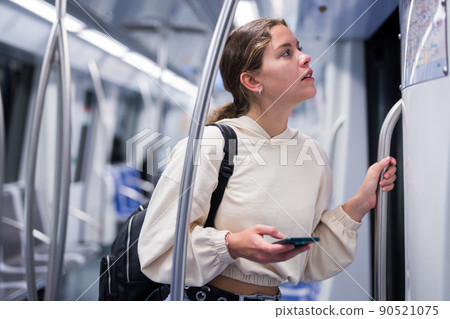 Portrait of a pensive girl with a mobile phone on a subway train Portrait of a pensive girl with a mobile phone on a subway train 90521075