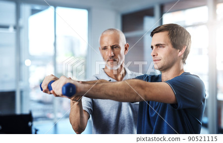 Working on joint mobilisation. Shot of a physiotherapist helping a patient work through his recovery with weights. Working on joint mobilisation. Shot of a physiotherapist helping a patient work through his recovery with weights. 90521115