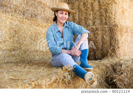 Asian woman farmer resting on hayloft Asian woman farmer resting on hayloft 90521124
