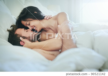 Can I give you a massage. Shot of an affectionate couple lying on their bed. Can I give you a massage. Shot of an affectionate couple lying on their bed. 90521142