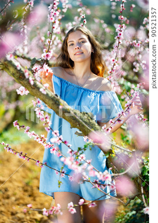 Portrait of young smiling woman in a garden with blooming peach 90521357