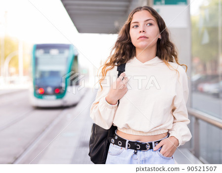 Woman waiting for tram on platform of public transport station Woman waiting for tram on platform of public transport station 90521507
