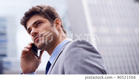 A smart phone for a savvy businessman. A low angle shot of a handsome young businessman using his cellphone in the city. 90521508