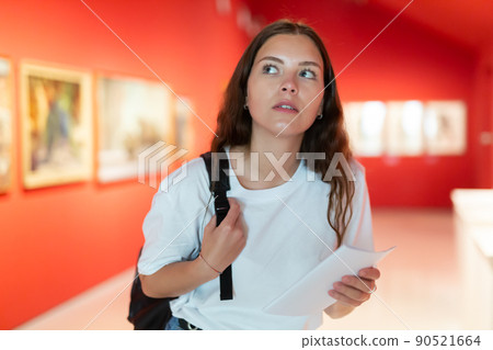 Thoughtful young girl in an art gallery studies works of art 90521664