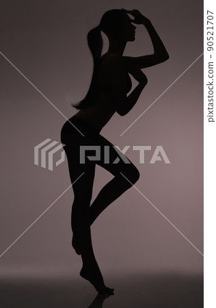 Silhouetted beauty. Studio silhouette of a beautiful woman in lingerie against a gray background. Silhouetted beauty. Studio silhouette of a beautiful woman in lingerie against a gray background. 90521707