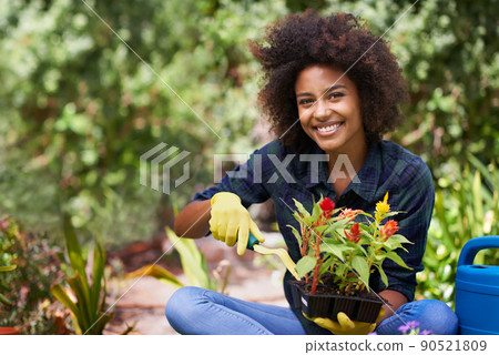 Shes got a green thumb. Portrait of a happy young woman and her tray of plants for the garden. Shes got a green thumb. Portrait of a happy young woman and her tray of plants for the garden. 90521809