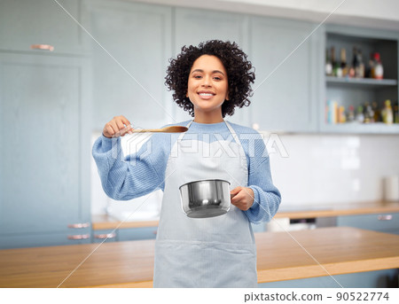 happy woman cooking food in saucepan in kitchen 90522774