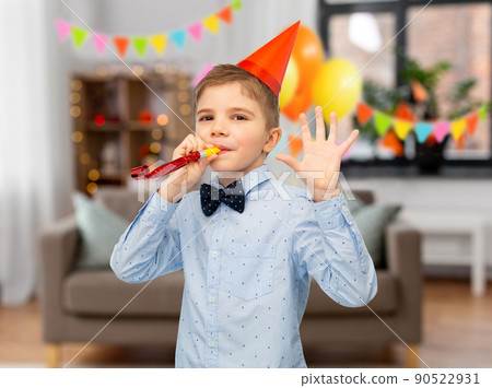 smiling boy in birthday party hat with blower smiling boy in birthday party hat with blower 90522931