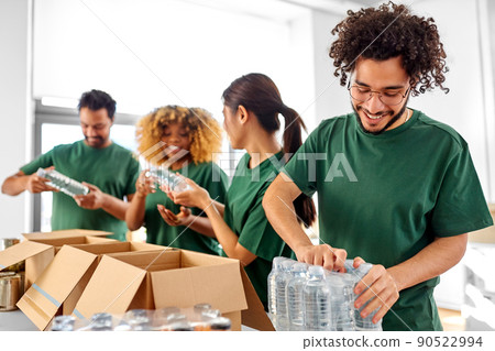 happy volunteers packing bottles of water in boxes happy volunteers packing bottles of water in boxes 90522994