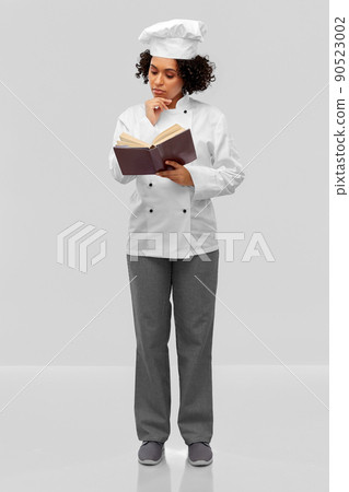 female chef in white toque reading cook book female chef in white toque reading cook book 90523002