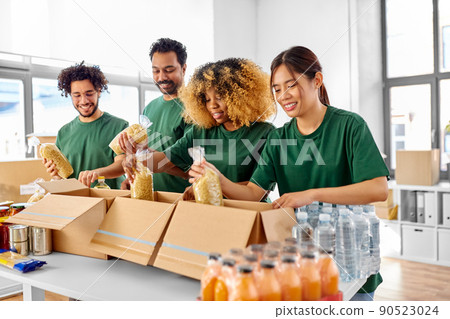 happy volunteers packing food in donation boxes happy volunteers packing food in donation boxes 90523024