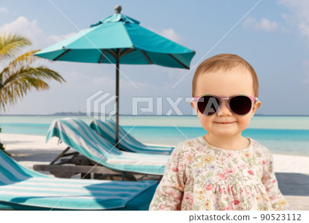 happy baby girl in sunglasses on summer beach 90523112