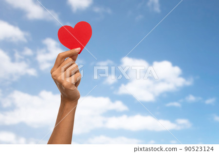 close up of hand holding red heart over blue sky close up of hand holding red heart over blue sky 90523124