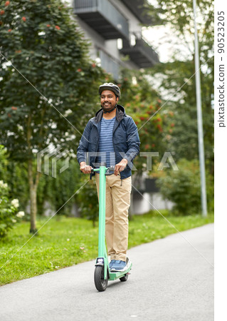 man in helmet riding electric scooter on street 90523205