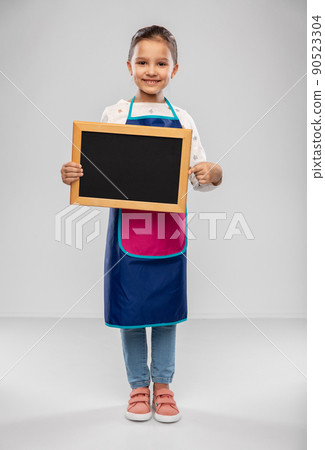 smiling little girl in apron holding chalkboard smiling little girl in apron holding chalkboard 90523304