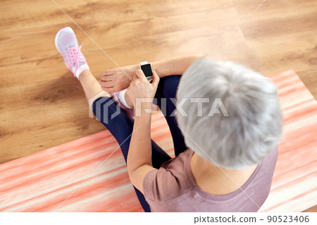 smiling senior woman with fitness tracker at home smiling senior woman with fitness tracker at home 90523406