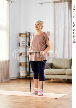 senior woman exercising with elastic band at home 90523425