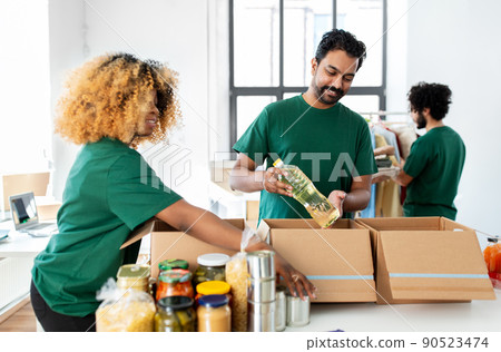 happy volunteers packing food in donation boxes happy volunteers packing food in donation boxes 90523474
