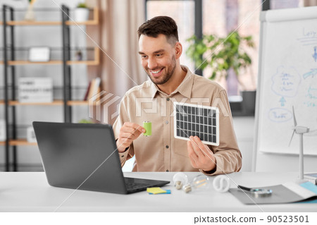 male teacher with laptop and solar battery at home 90523501