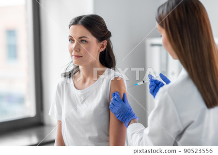 female doctor with syringe vaccinating patient 90523556