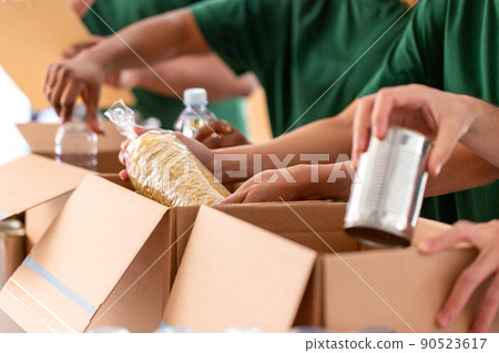 close up of volunteers packing food in boxes 90523617