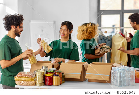 happy volunteers packing food and clothes in boxes happy volunteers packing food and clothes in boxes 90523645