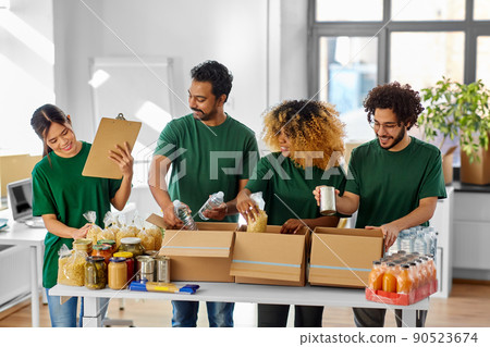 happy volunteers packing food in donation boxes happy volunteers packing food in donation boxes 90523674